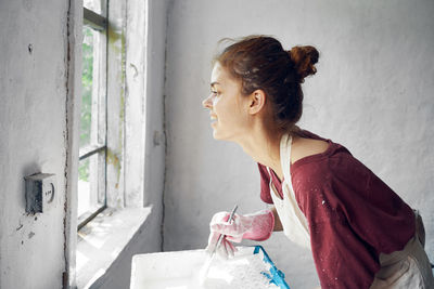 Side view of young woman drinking water at home