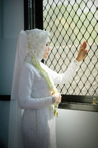 Side view of woman standing against white wall