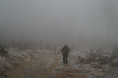 Rear view of people walking on snow covered land