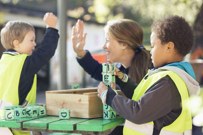 Teacher giving high-five to student while boy arranging blocks at table