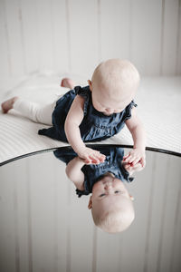 Baby girl looking at reflection in mirror