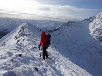 Rear view of man walking on snowcapped mountain