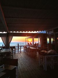 Chairs and tables in restaurant against sea at sunset