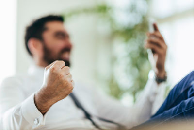 Low angle view of businessman clinching fist while using mobile phone