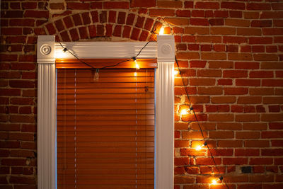 Illuminated lamp on brick wall