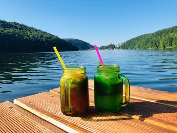 Two glasses of lemonade on wooden pontoon near the lake