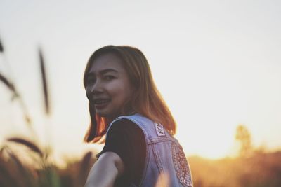 Young man looking away against sky during sunset