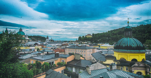 Buildings in town against cloudy sky