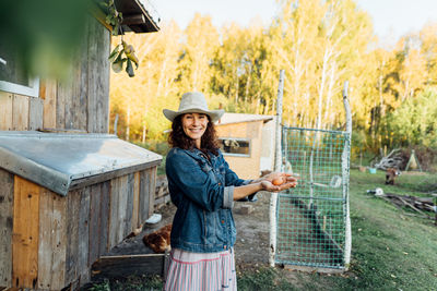 Portrait of young woman standing by fence