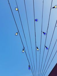 Low angle view of power lines against clear blue sky