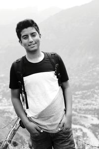 Portrait of young man standing against mountain