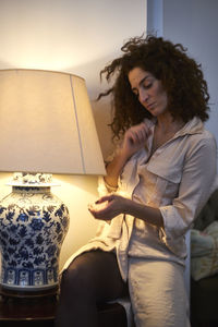 Mature woman standing by illuminated electric lamp at home