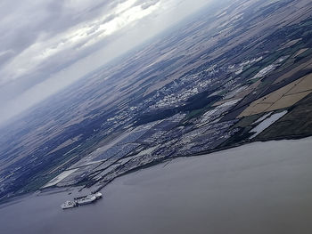 Aerial view of sea by snowcapped mountain against sky