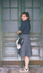 Portrait of smiling young woman standing at entrance