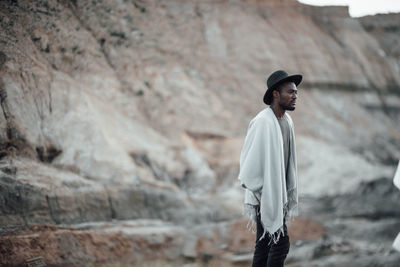 Side view of young man standing on rock