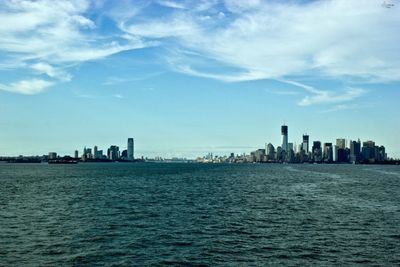 City at waterfront against cloudy sky