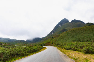 Road leading towards mountains against sky