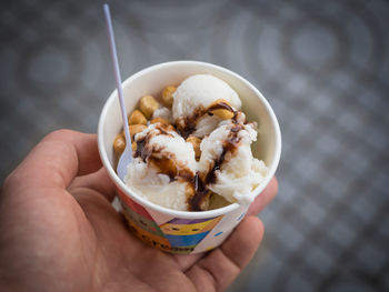 Close-up of hand holding ice cream in bowl