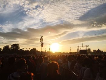 Crowd at music concert against sky during sunset