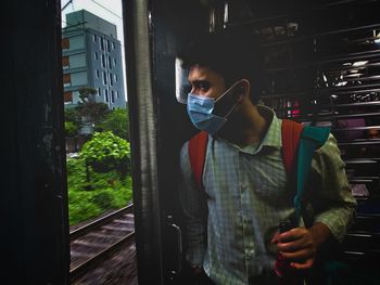 Side view of young man standing in local a train