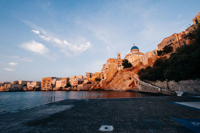 View of buildings at waterfront against cloudy sky