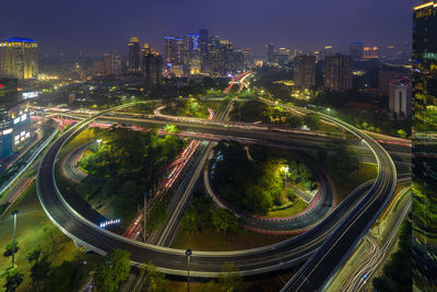 High angle view of illuminated street amidst buildings in city at night