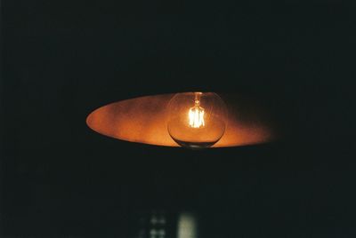 Low angle view of illuminated lamp against black background