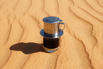 High angle view of coffee cup on sand