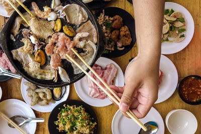 Bbq barbecue eating. people grilling  pork, meal, shellfish and shrimp with wooden chopsticks.