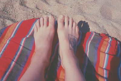 Low section of woman relaxing on blanket at beach