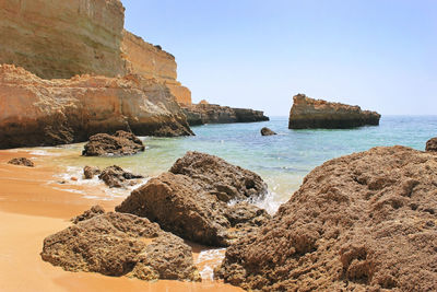 Rocks on beach against clear sky