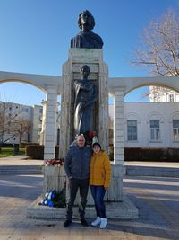 Full length of friends standing outside temple against clear sky