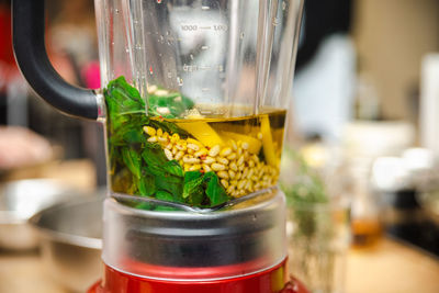 Close up of a blender with ingredients for making pesto sauce.