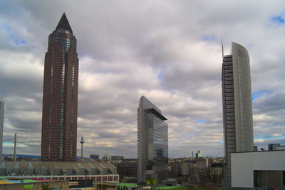 Low angle view of skyscrapers against cloudy sky