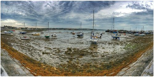 Boats in sea against cloudy sky