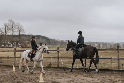 View of girls horseback riding on paddock