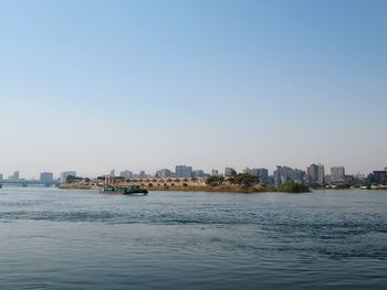 Sea by buildings against clear sky