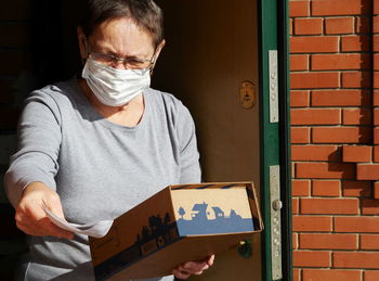 Midsection of man holding paper while standing against wall