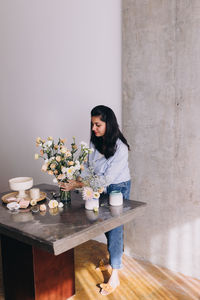 Female florist working standing up, arranging flowers in a vase