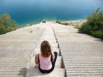 Rear view of women sitting on steps against sea