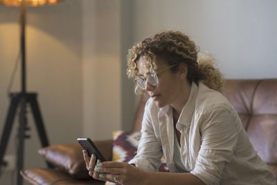 Young woman using mobile phone while sitting at home