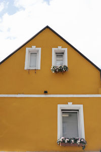 Low angle view of yellow house against sky