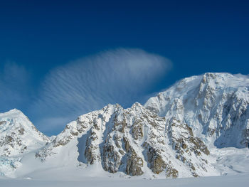 Scenic view of snowcapped mountains against blue sky