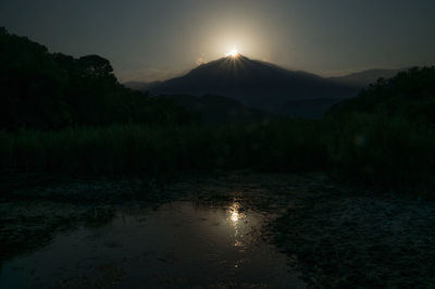 Scenic view of lake and mountains against sky at sunset