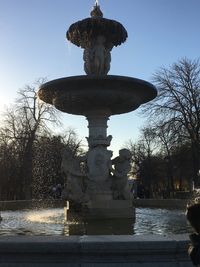 Low angle view of statue by fountain against sky