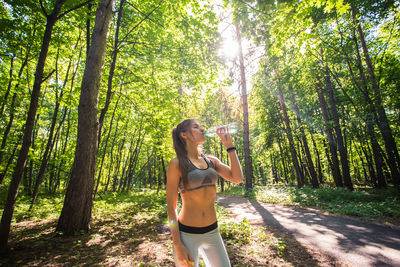 Full length of woman standing amidst trees in forest