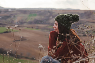 Woman looking away while sitting on land