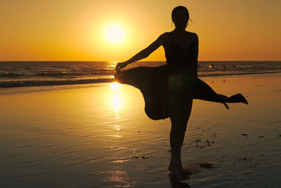 Silhouette man on beach against sky during sunset