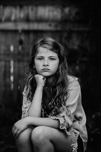 Portrait of cute girl with hand on chin sitting at home