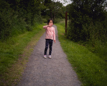 Full length of girl standing on road amidst trees